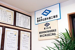 株式会社清水 賞状と共に壁に飾られている三協工業の市認定水道工事店（豊栄市当時）の看板